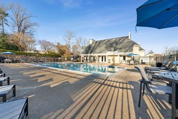 A swimming pool with chairs and umbrellas in front of a house